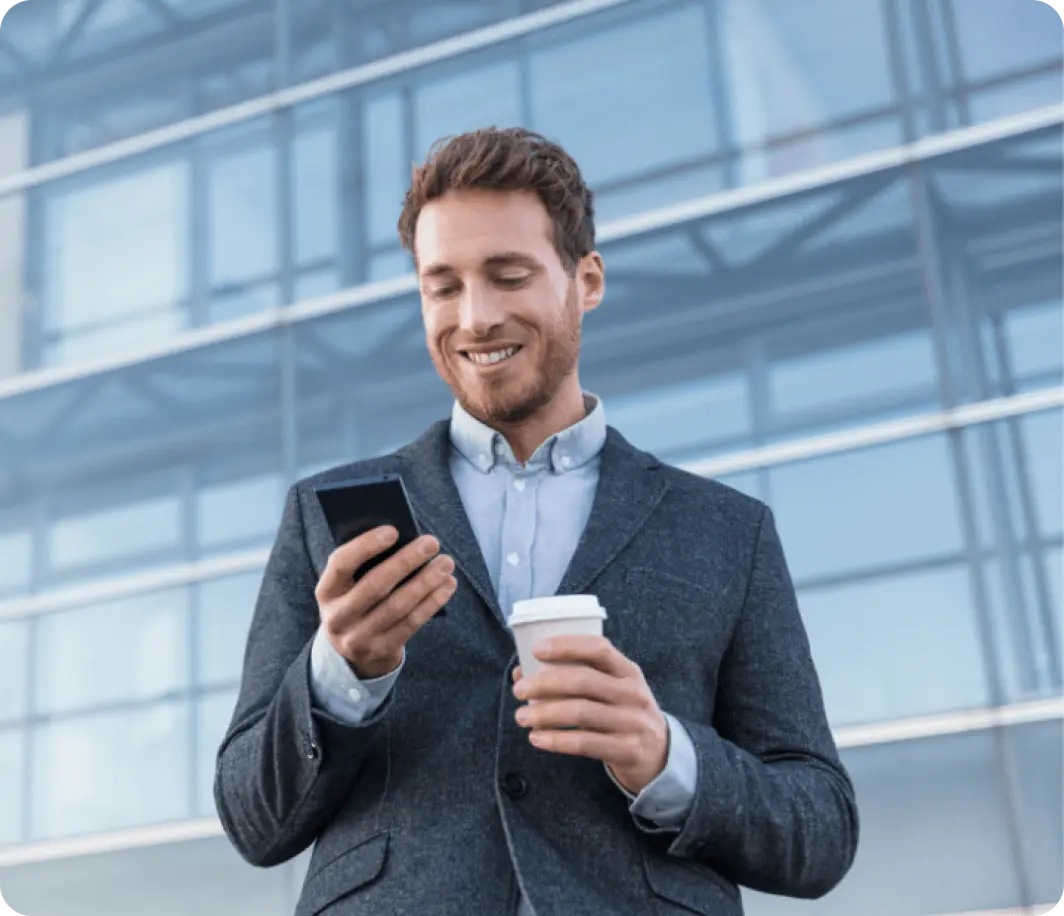 A businessman holding a cup of coffee and looking at his phone