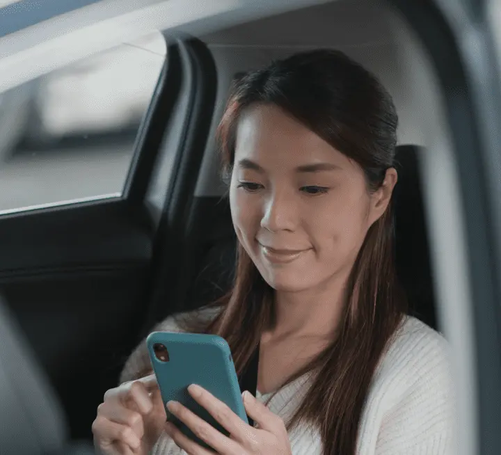 A woman in a car looking at her phone