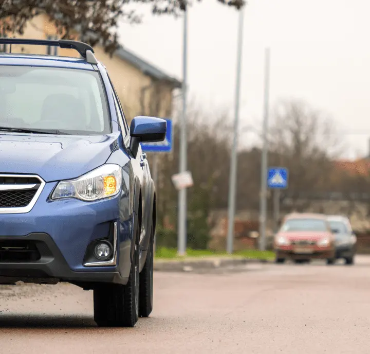 A blue subaru is parked on a street