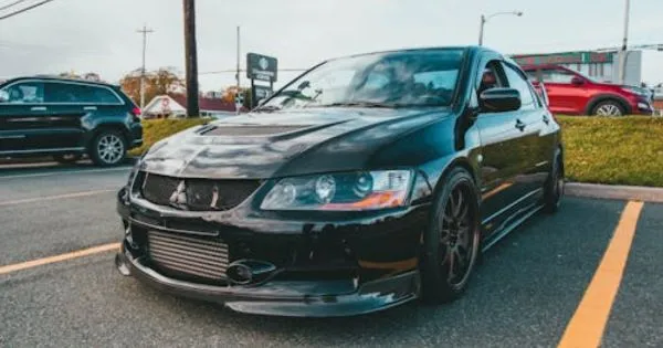 A Black Car Parked In An Urban Parking Lot With Some Other Vehicles A Black Car Parked In An Urban Parking Lot With Some Other Vehicles