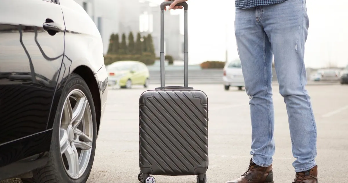 A Man In An Airport Parking Lot With His Suitcase A Man In An Airport Parking Lot With His Suitcase