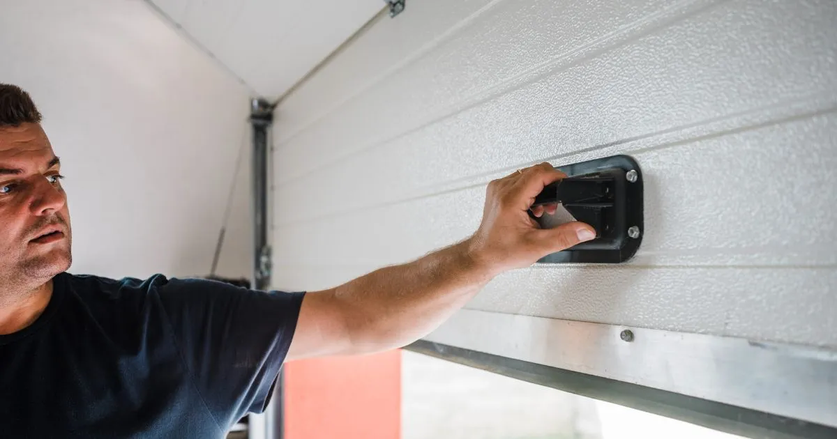 A Man Installing A Sensing Device On His Garage Door To Make It More Secure A Man Installing A Sensing Device On His Garage Door To Make It More Secure