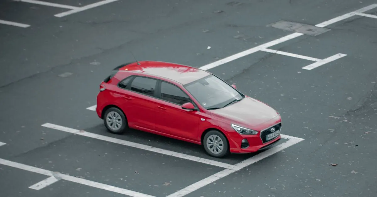 A Red Car Parked In An Uncovered Parking Lot With Many Empty Spaces Available For Booking A Red Car Parked In An Uncovered Parking Lot With Many Empty Spaces Available For Booking