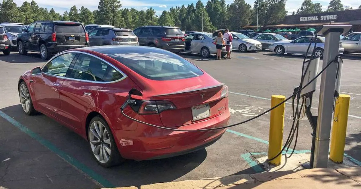 A Red Electric Car Getting Charged While Being Parked In A Parking Lot